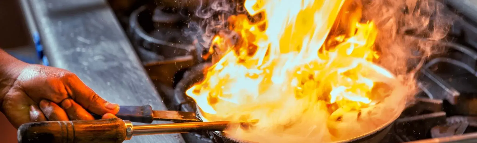 hand tosses pan on stove filled with fire