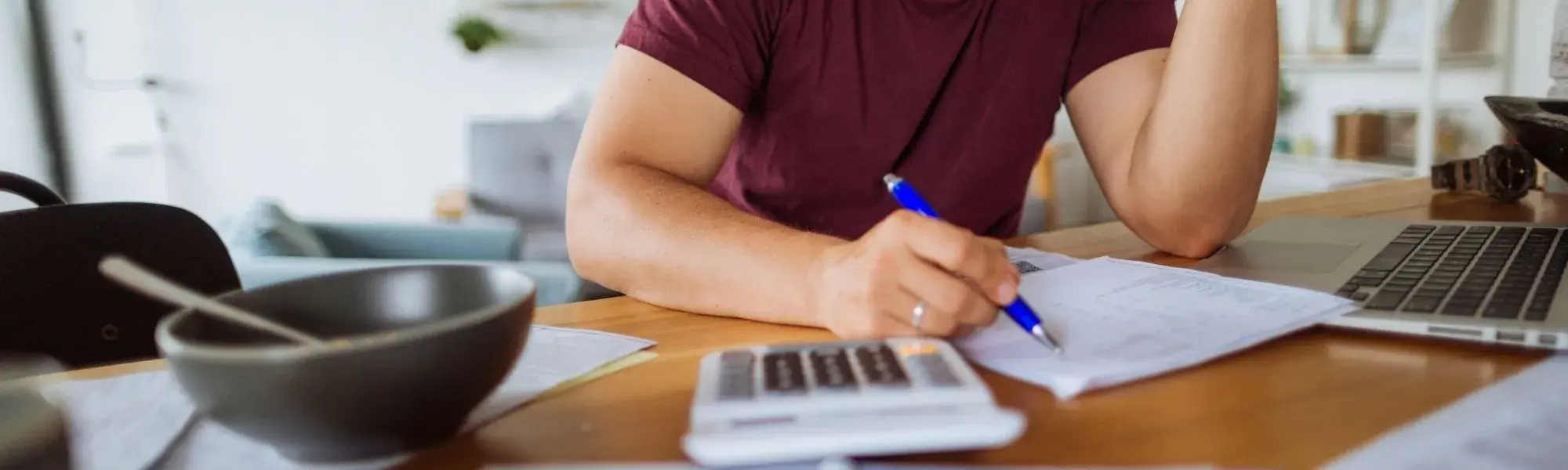 Man pays bills at a table covered in papers
