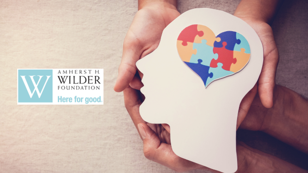 Hands holding a cutout of head with heart of puzzle pieces for brain; Wilder Research logo