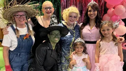 Power of the Purse attendees pose dressed as the scarecrow, Elphaba, Madame Morrible, and Glinda 