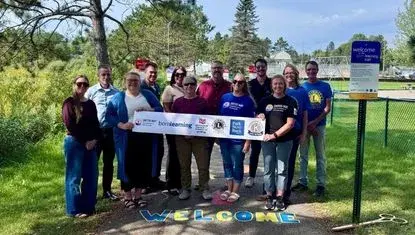 Representatives from the Chisholm Community Foundation, Chisholm Lions Club, Kiwanis Club of Chisholm, Park State Bank, City of Chisholm, and United Way of Northeastern Minnesota prepare for a ribbon cutting September 11 at the new Born learning Trail near Longyear  Lake Park.